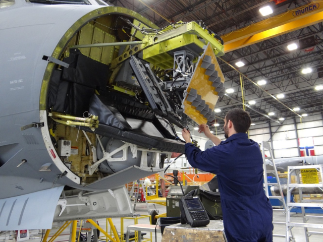 IMP Aerospace & Defence technician installing a radar component on a military aircraft nose section in a maintenance hangar
